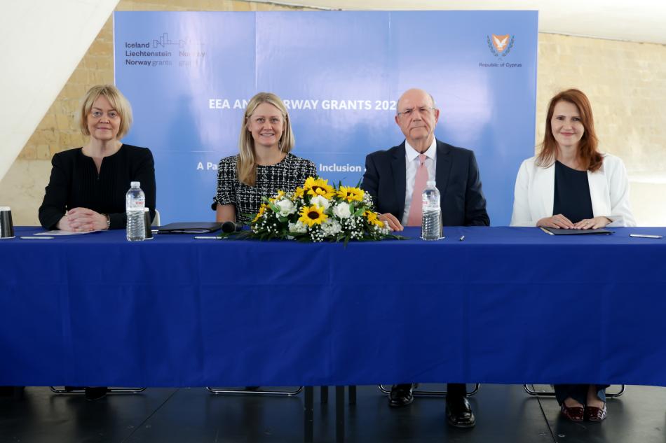 People sitting at table looking into camera after signing MoU